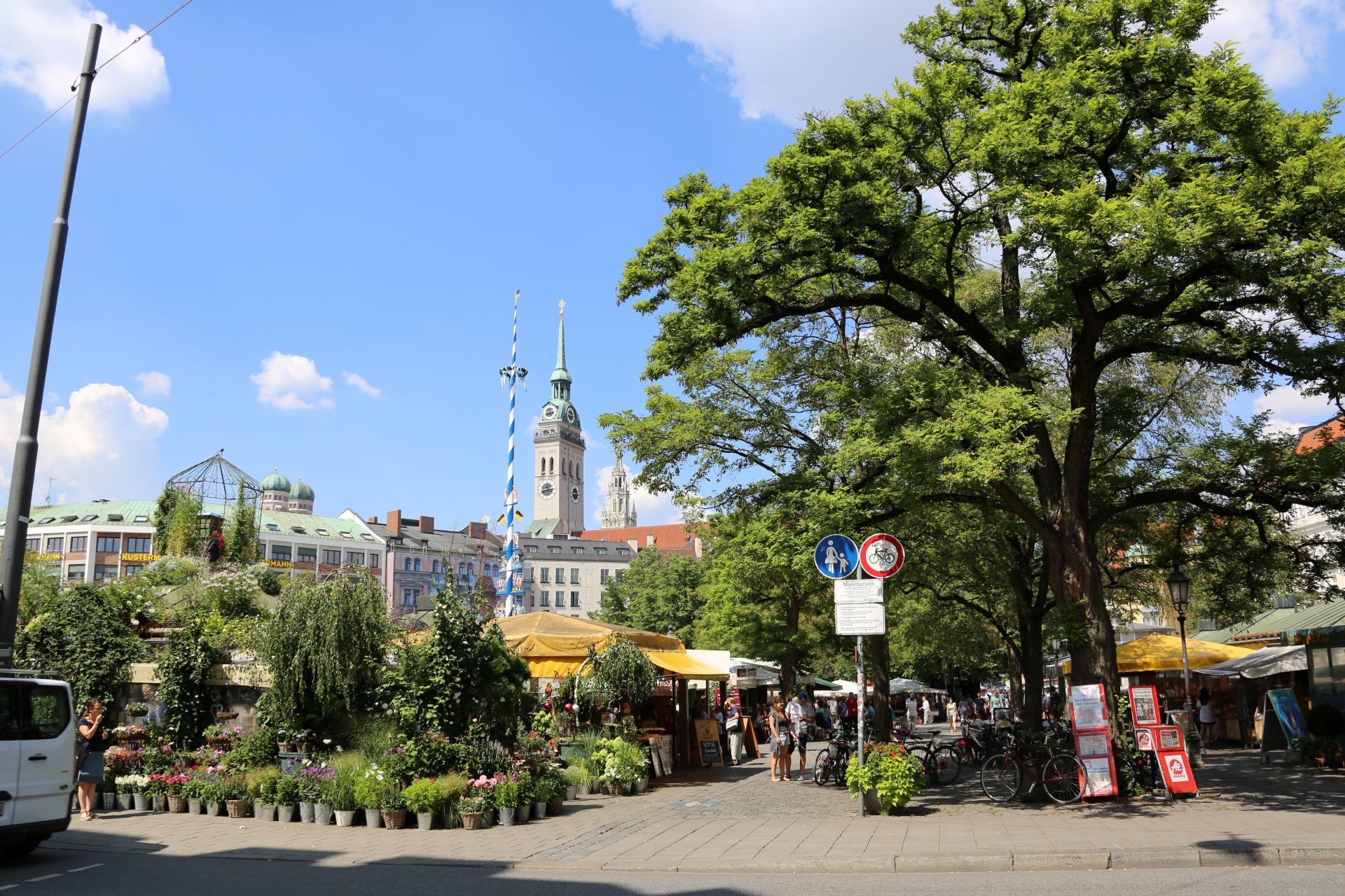 Blick auf den Viktualienmarkt in München mit Maibaum und Marktständen – beliebter Treffpunkt für Genießer und Besucher mit Escort Muenchen.